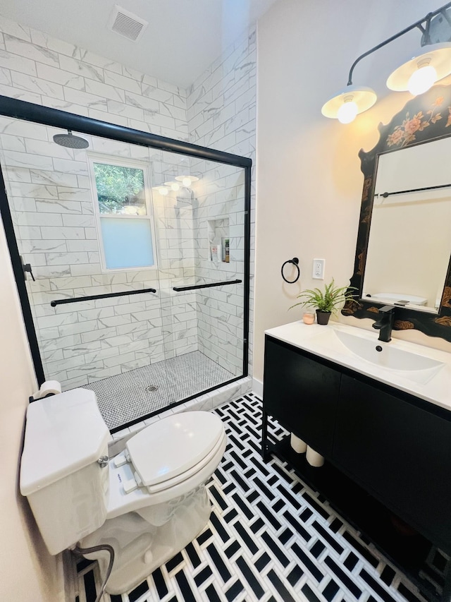 bathroom with vanity, a shower with door, and toilet