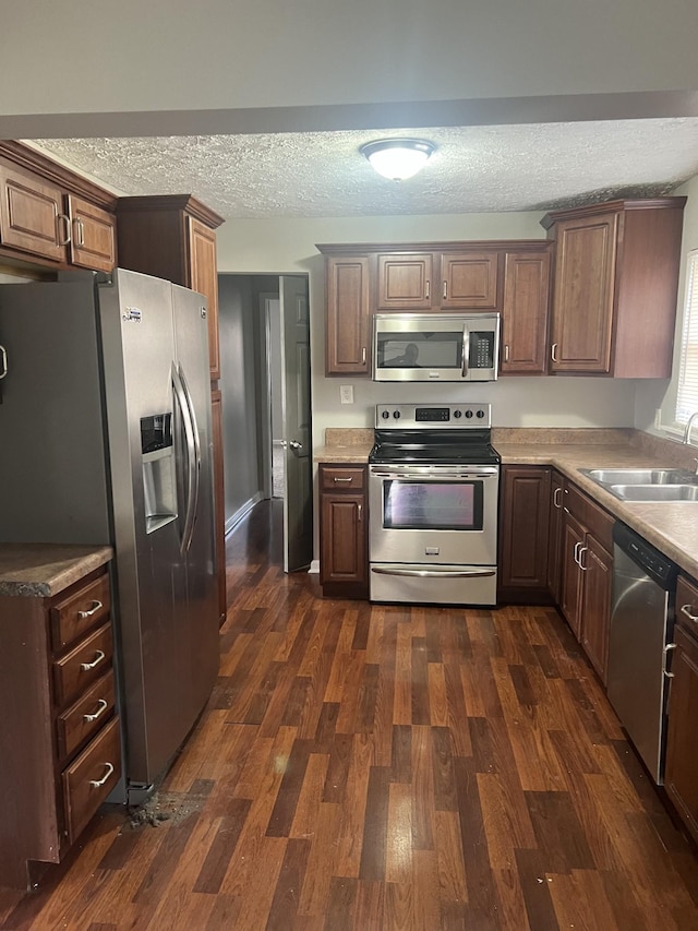 kitchen with sink, stainless steel appliances, dark hardwood / wood-style floors, and a textured ceiling