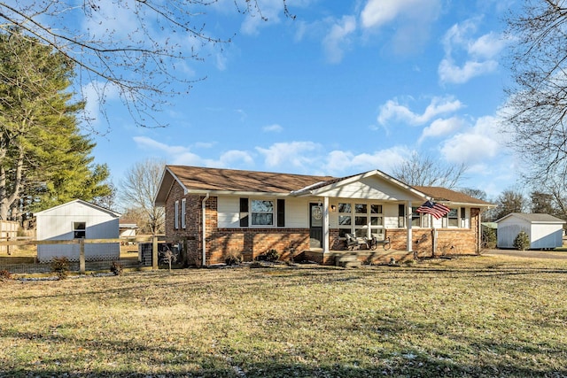 view of front of house featuring a porch, a front yard, and a storage shed