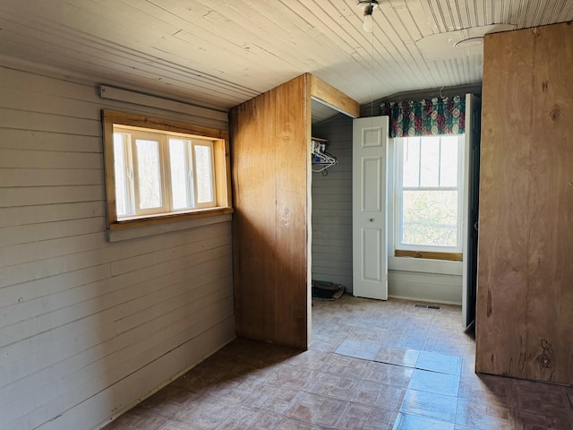 interior space featuring wooden ceiling, wooden walls, and a closet