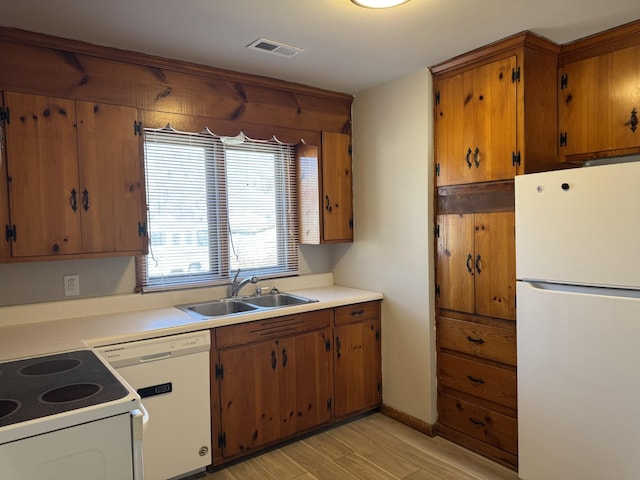 kitchen with white appliances, sink, and light wood-type flooring