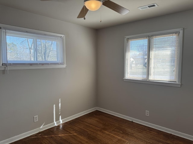 spare room featuring ceiling fan, a healthy amount of sunlight, and dark hardwood / wood-style floors