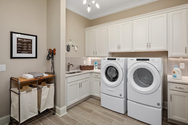 clothes washing area featuring cabinets, ornamental molding, washer and clothes dryer, and sink