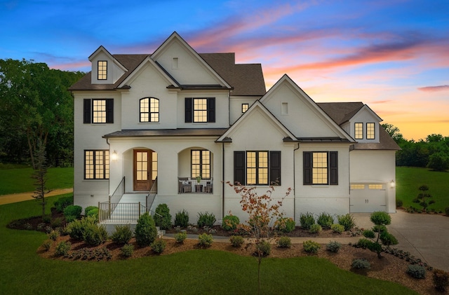 french country style house featuring a garage and a lawn