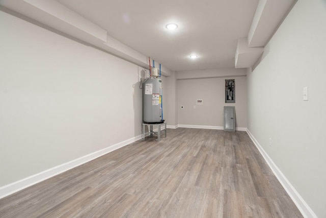 basement featuring water heater and hardwood / wood-style flooring