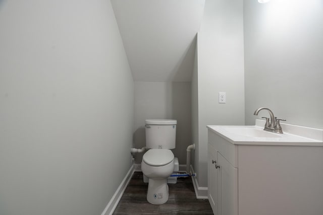 bathroom featuring vanity, wood-type flooring, vaulted ceiling, and toilet