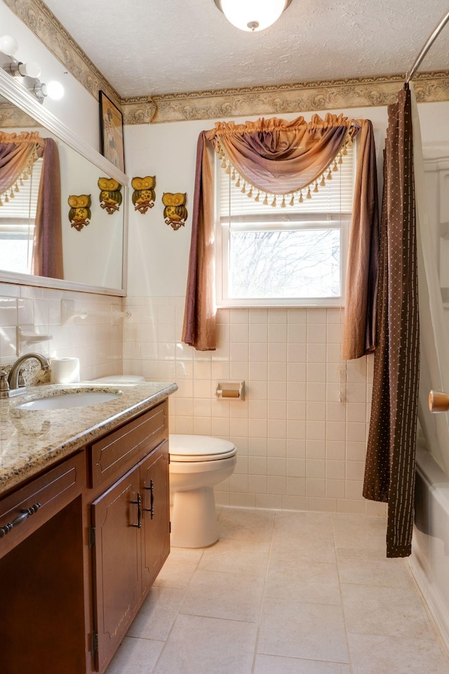 full bathroom with toilet, tile walls, a textured ceiling, vanity, and tile patterned flooring