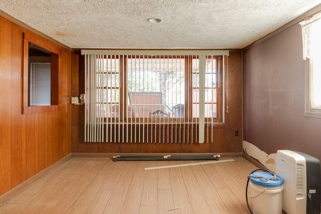 interior space with plenty of natural light, ornamental molding, wooden walls, and wood-type flooring