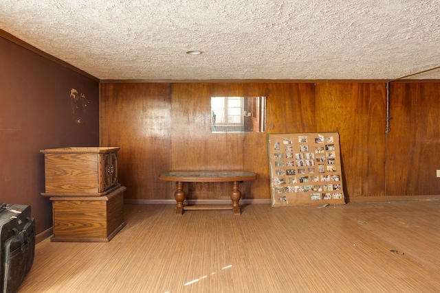 miscellaneous room featuring light hardwood / wood-style floors, a textured ceiling, and wood walls