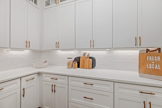 kitchen with light stone countertops, white cabinets, and backsplash