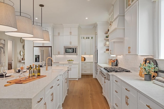 kitchen featuring appliances with stainless steel finishes, decorative light fixtures, white cabinetry, sink, and backsplash