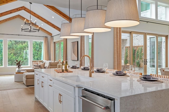 kitchen with decorative light fixtures, white cabinetry, sink, a kitchen island with sink, and light stone counters