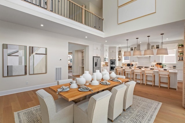 dining area featuring a towering ceiling and light hardwood / wood-style floors