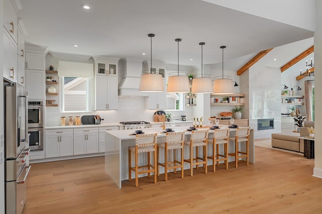 kitchen with a breakfast bar, white cabinetry, hanging light fixtures, lofted ceiling with beams, and a kitchen island