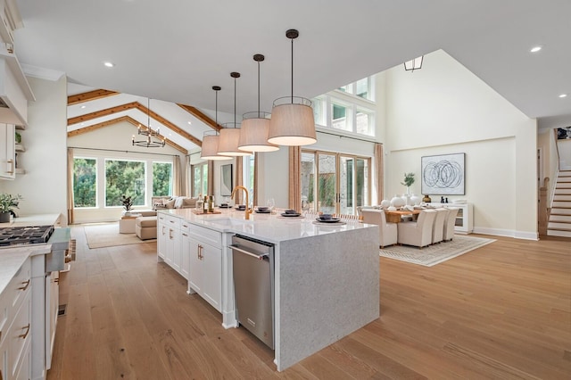 kitchen featuring pendant lighting, lofted ceiling with beams, an island with sink, white cabinetry, and sink