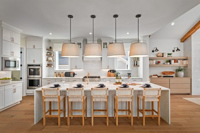 kitchen featuring an island with sink, appliances with stainless steel finishes, a breakfast bar area, and light hardwood / wood-style floors