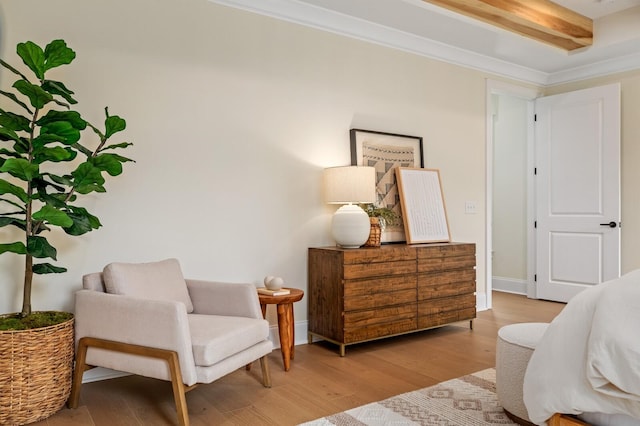 sitting room featuring beamed ceiling, ornamental molding, and light hardwood / wood-style flooring