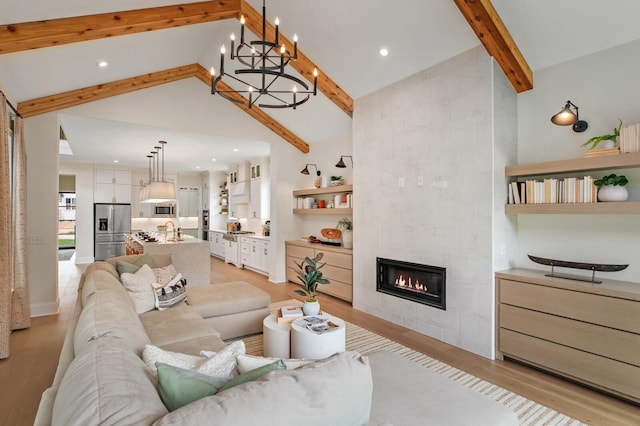 living room with sink, high vaulted ceiling, light hardwood / wood-style flooring, beam ceiling, and a tiled fireplace