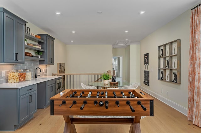 recreation room with sink and light hardwood / wood-style flooring