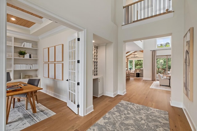 interior space with beam ceiling, a towering ceiling, wood ceiling, and light wood-type flooring