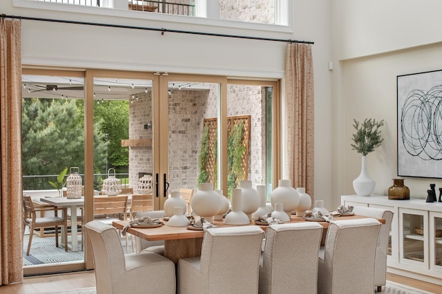 dining space with a high ceiling, a healthy amount of sunlight, and light wood-type flooring