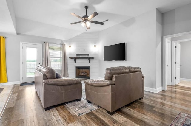 living room featuring hardwood / wood-style flooring, lofted ceiling, a large fireplace, and ceiling fan