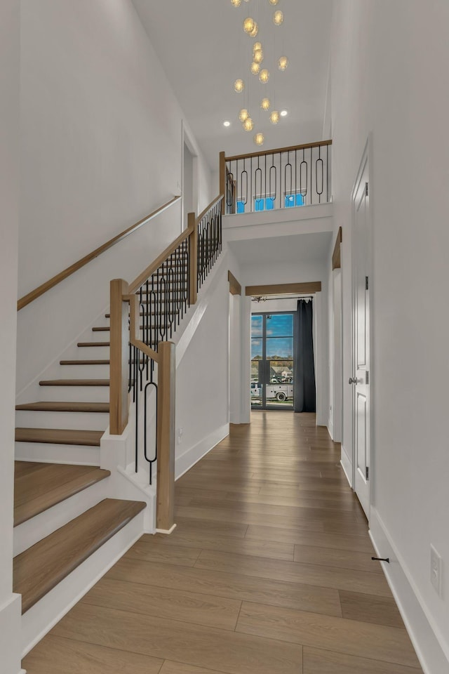 foyer entrance with a high ceiling, hardwood / wood-style floors, and a chandelier