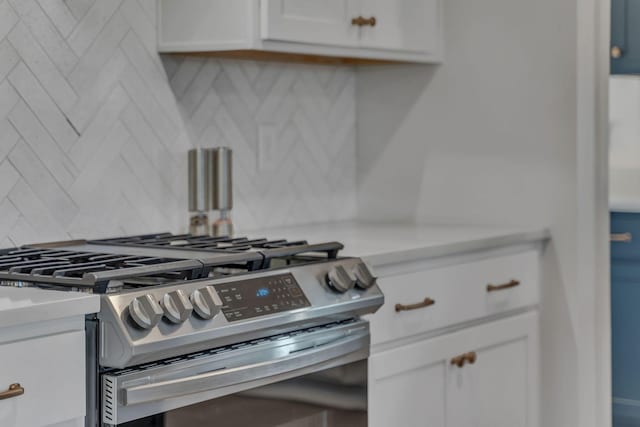 interior details with decorative backsplash, stainless steel range with gas cooktop, and white cabinets