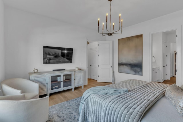 bedroom featuring connected bathroom, a notable chandelier, and light hardwood / wood-style floors