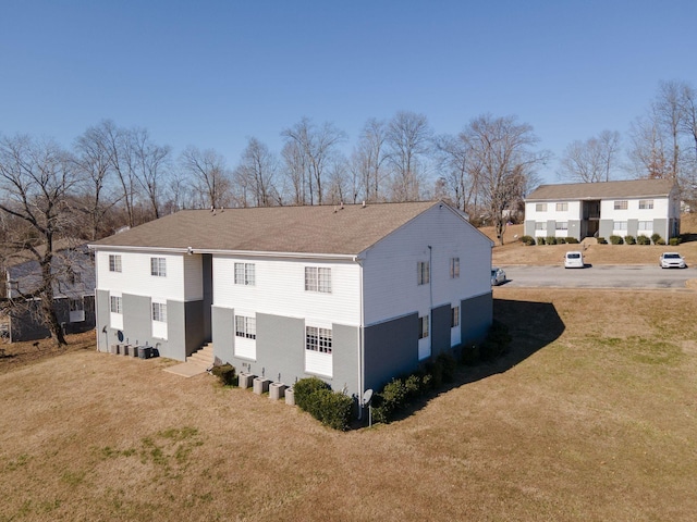 rear view of property featuring central AC and a lawn