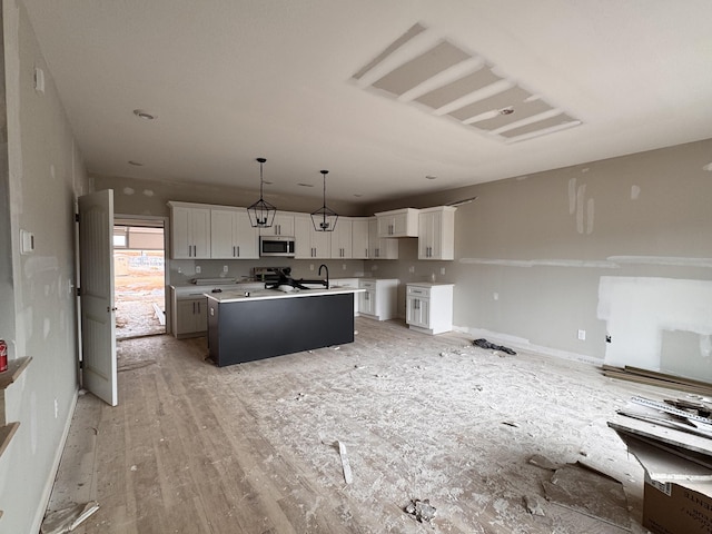 2363 Pea Ridge Rd, Clarksville, TN 37040 - kitchen with stainless steel microwave, a center island with sink, white cabinetry, and pendant lighting
