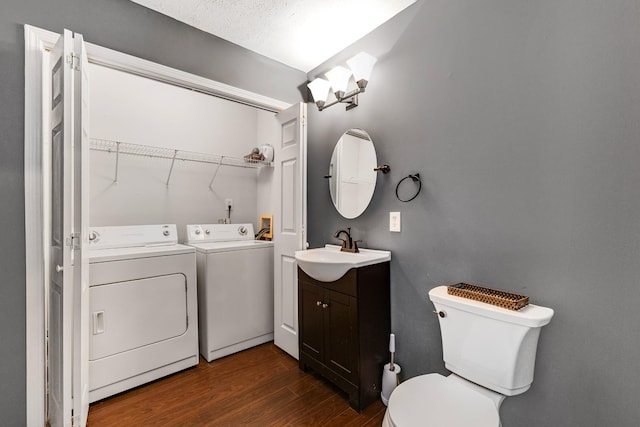 bathroom with vanity, wood-type flooring, a textured ceiling, separate washer and dryer, and toilet