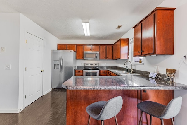 kitchen featuring sink, kitchen peninsula, stainless steel appliances, dark wood-type flooring, and a textured ceiling