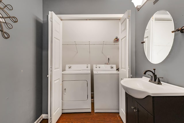 clothes washing area featuring washing machine and dryer, sink, and dark hardwood / wood-style floors