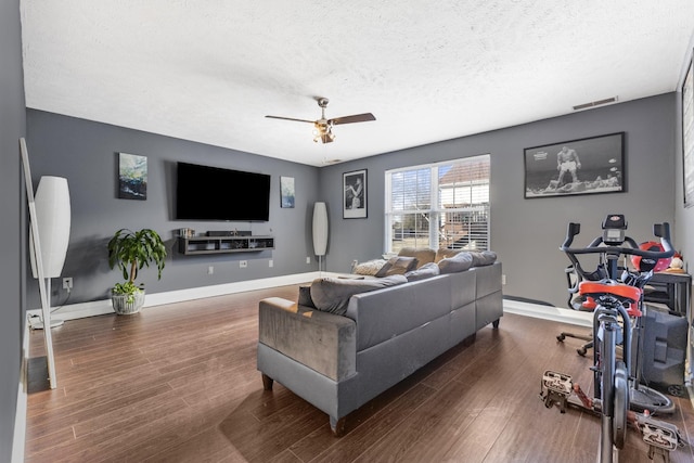 living room with dark wood-type flooring, a textured ceiling, and ceiling fan