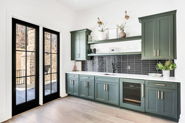 bar with sink, green cabinets, beverage cooler, and decorative backsplash