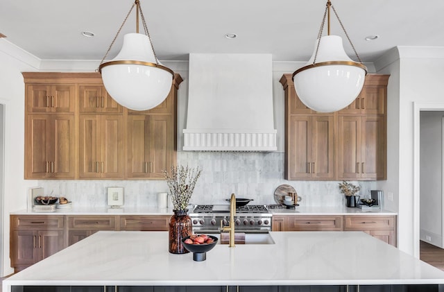 kitchen featuring custom exhaust hood, tasteful backsplash, a center island with sink, and decorative light fixtures