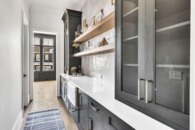 bar with backsplash and light hardwood / wood-style flooring