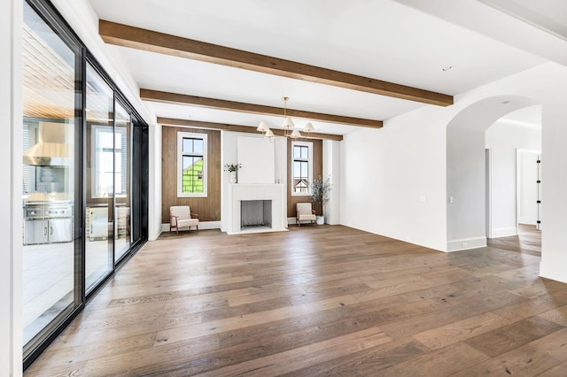 unfurnished living room featuring dark hardwood / wood-style floors, a chandelier, and beam ceiling