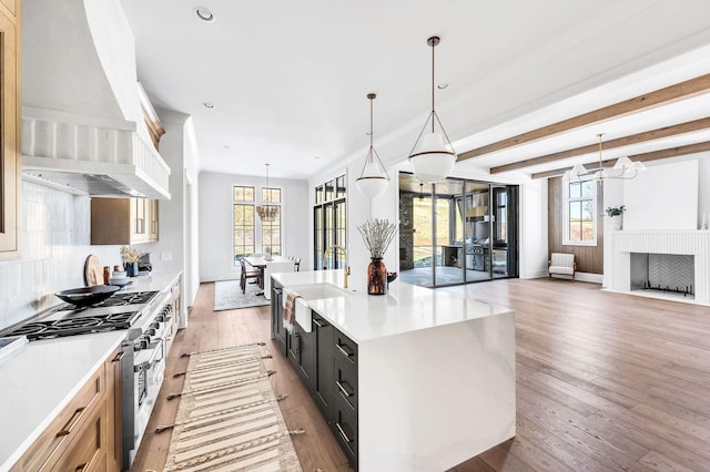 kitchen with double oven range, plenty of natural light, custom range hood, and decorative light fixtures