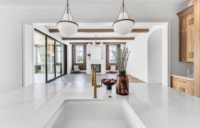 interior space featuring light stone counters, sink, hanging light fixtures, and light brown cabinets