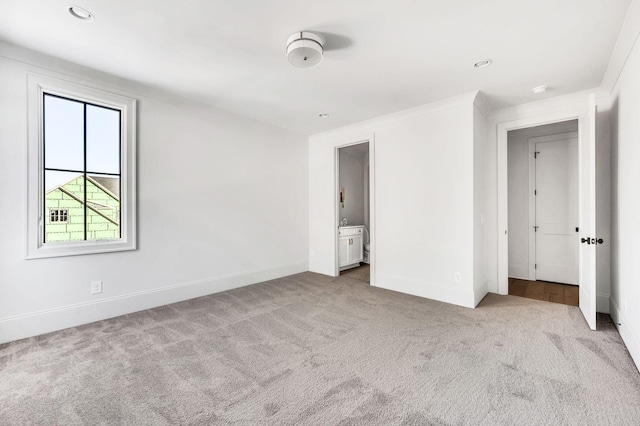 unfurnished bedroom with ornamental molding, light carpet, and ensuite bath