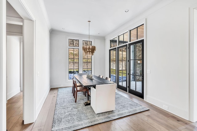 dining space with a notable chandelier, crown molding, and light hardwood / wood-style flooring