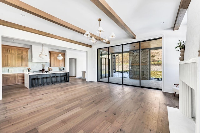 unfurnished living room featuring an inviting chandelier, wood-type flooring, beam ceiling, and floor to ceiling windows