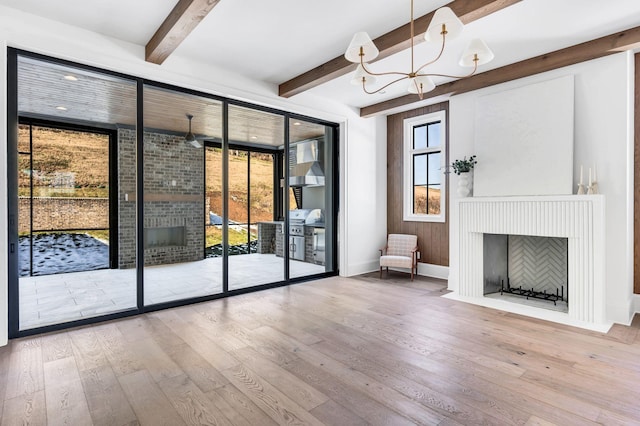 unfurnished living room featuring beamed ceiling, wood-type flooring, and a chandelier