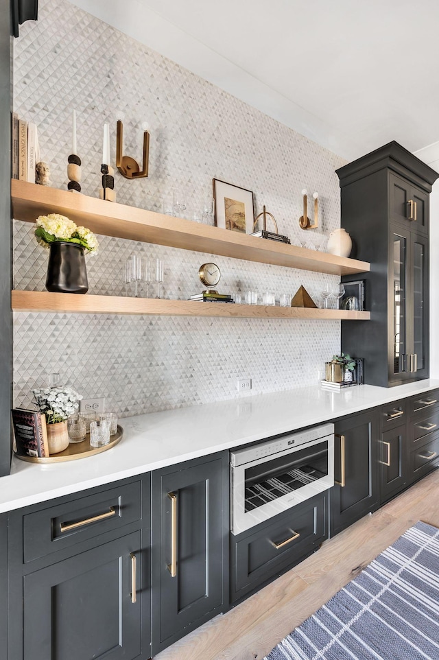 bar featuring tasteful backsplash and light hardwood / wood-style flooring