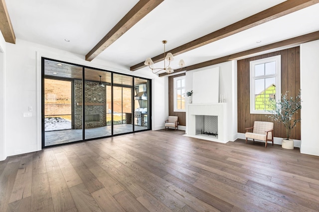 unfurnished living room featuring an inviting chandelier and dark hardwood / wood-style flooring