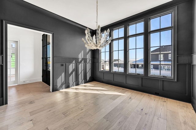 unfurnished dining area with light hardwood / wood-style floors and a chandelier