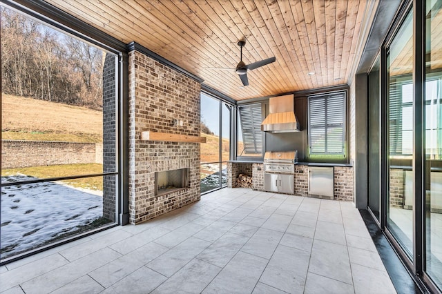 unfurnished sunroom featuring a healthy amount of sunlight, wooden ceiling, and ceiling fan