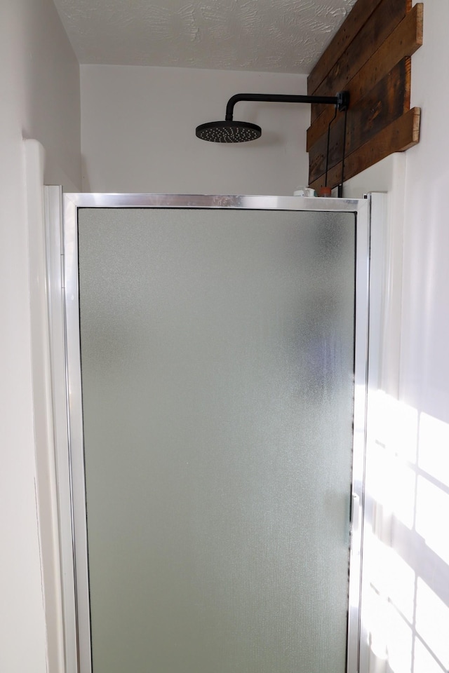 bathroom featuring a shower with shower door and a textured ceiling